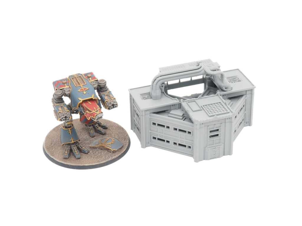 Grey 3D-printed sci-fi building terrain piece next to a painted miniature mech for scale