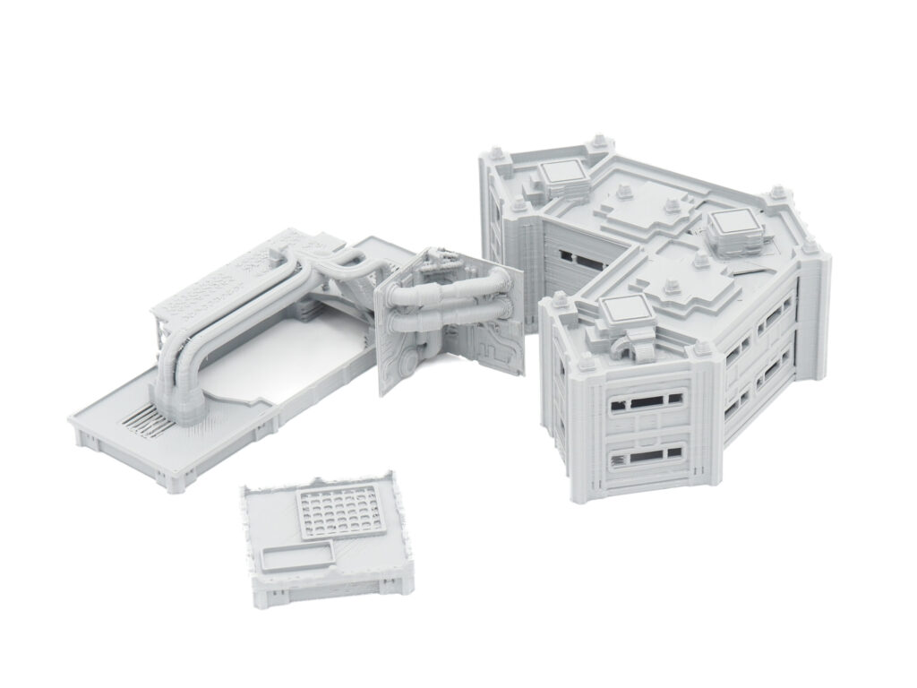 Grey 3D-printed sci-fi modular building and industrial pipe terrain pieces for tabletop gaming