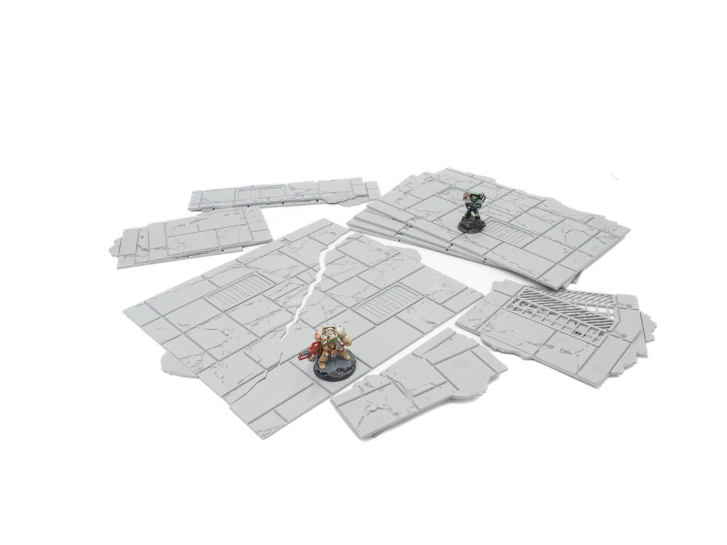 Grey 3D printed modular sci-fi floor tiles with cracked details, shown with miniature gaming figures for scale