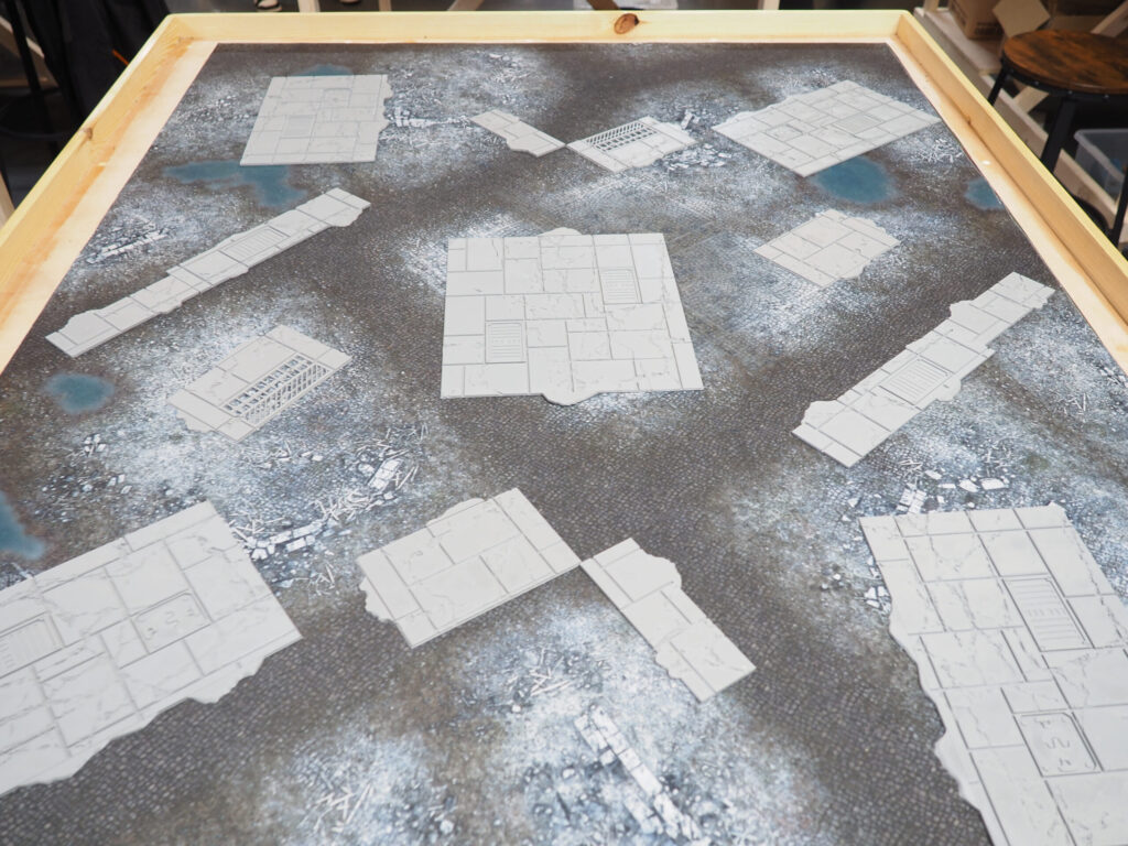 Grey 3D-printed modular stone tiles and paths for tabletop gaming, arranged on a textured battle mat