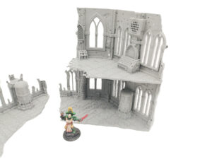Grey 3D-printed gothic ruin miniature terrain with two levels, shown with a painted figure for scale