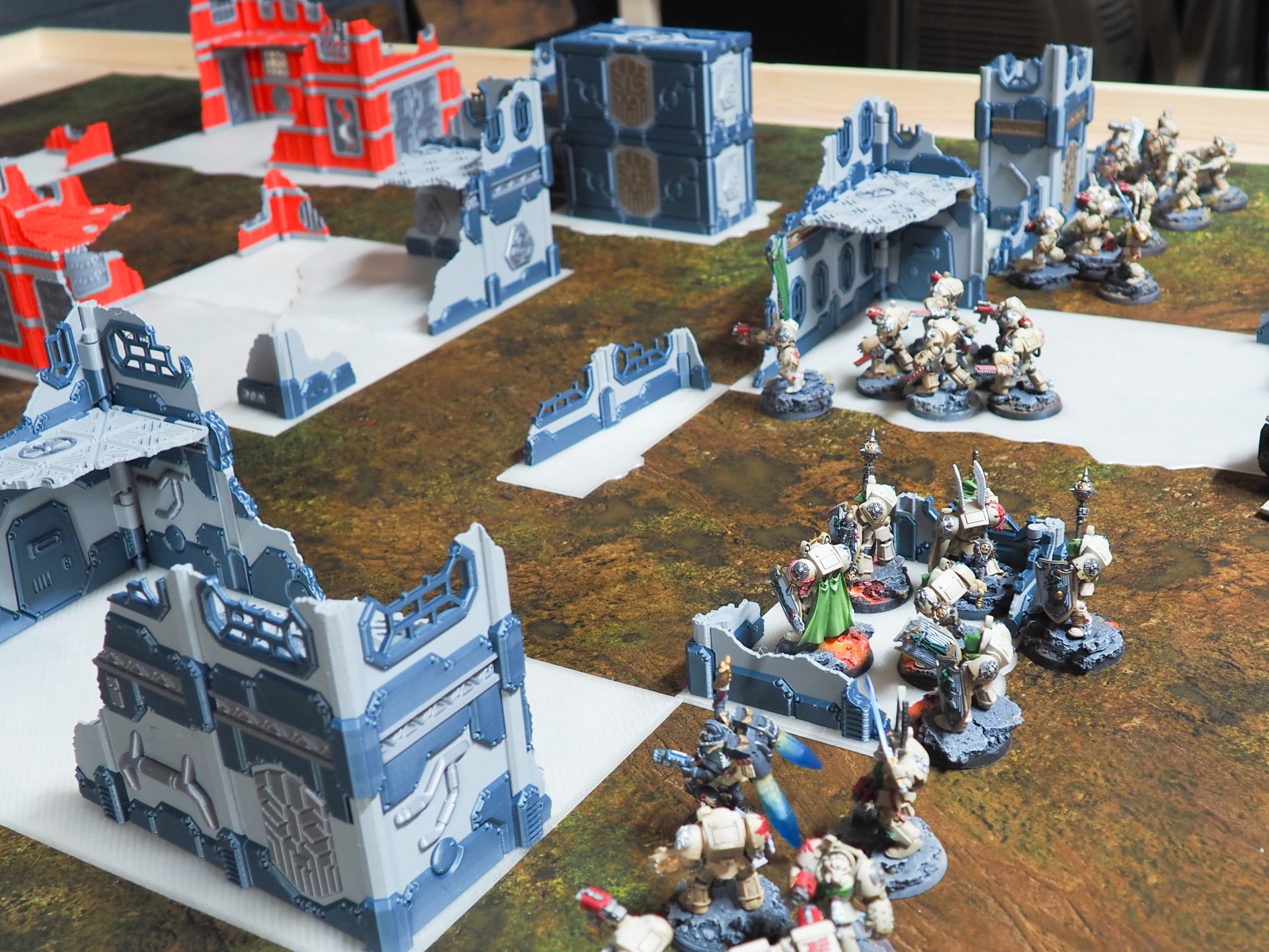 3D-printed sci-fi ruined terrain and barricades arranged on a tabletop battlefield with miniature figurines