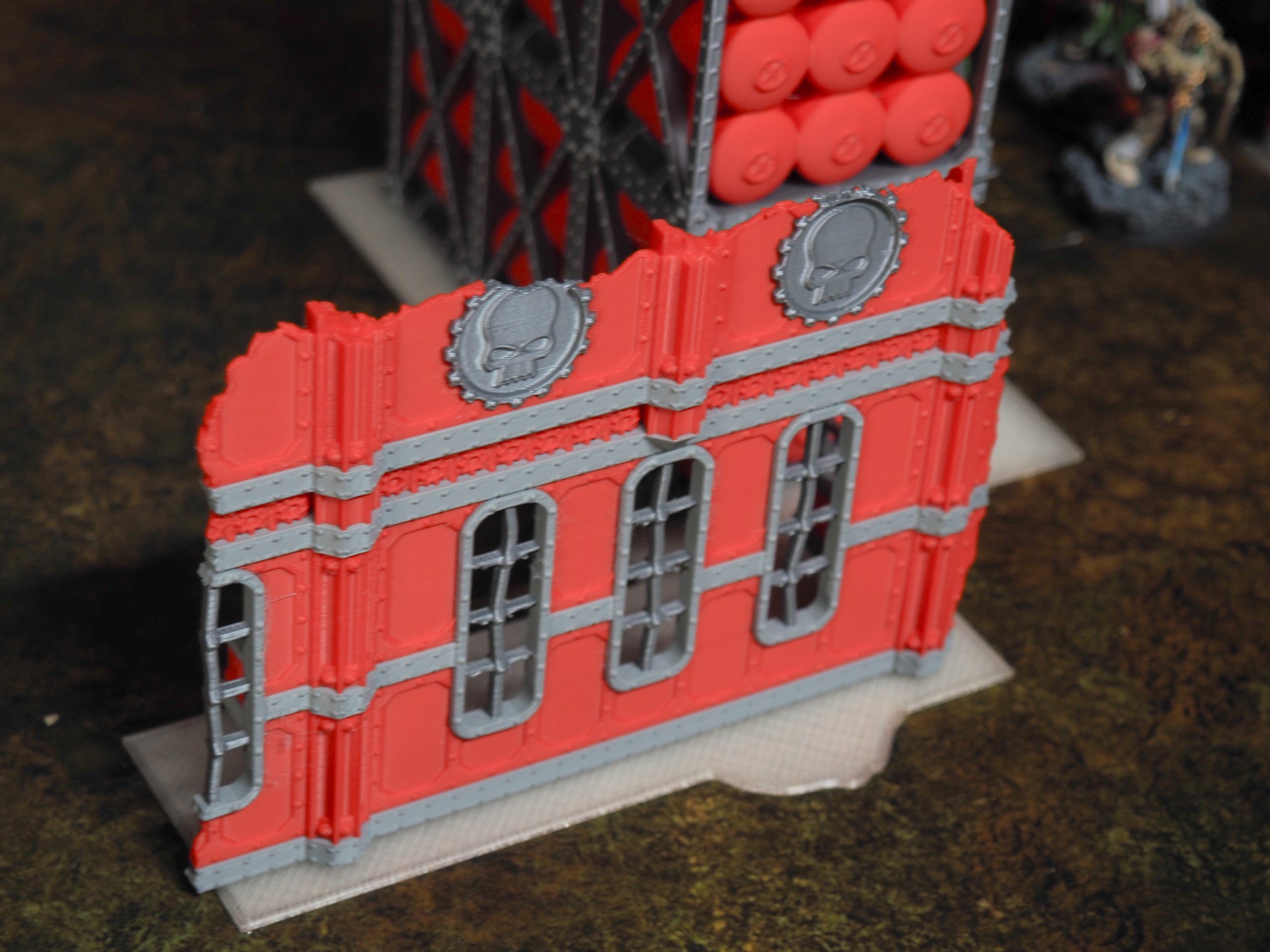 3D-printed red and grey ruined sci-fi Gothic wall terrain with arched windows and skull emblems for tabletop wargaming
