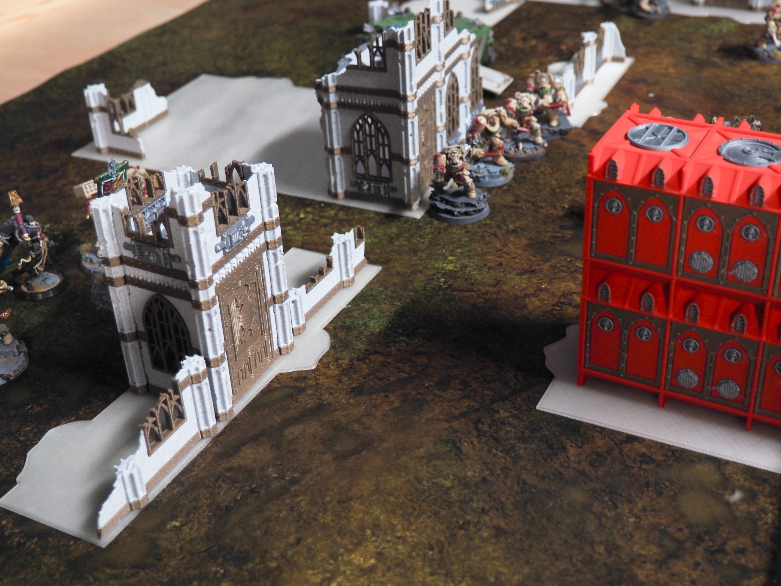3D printed gothic ruins and modular building terrain on a tabletop wargaming battlefield with miniature figures