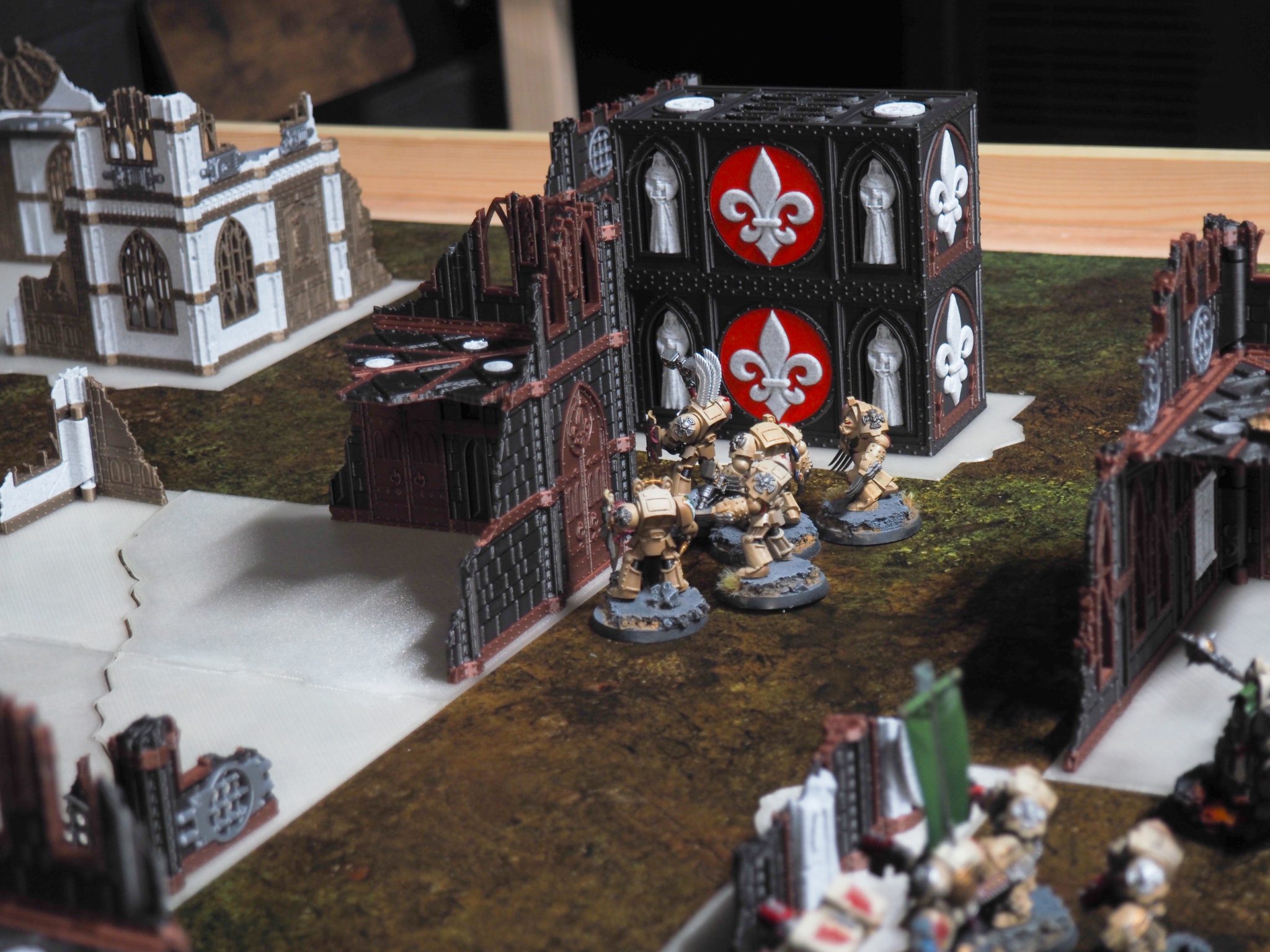 3D-printed gothic ruin tabletop terrain with fleur-de-lis motifs, shown with painted sci-fi miniatures on a battle mat
