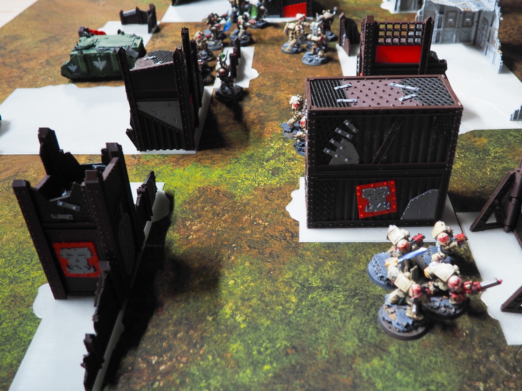 3D-printed tabletop wargaming terrain and industrial fortifications set up on a battle mat with miniatures