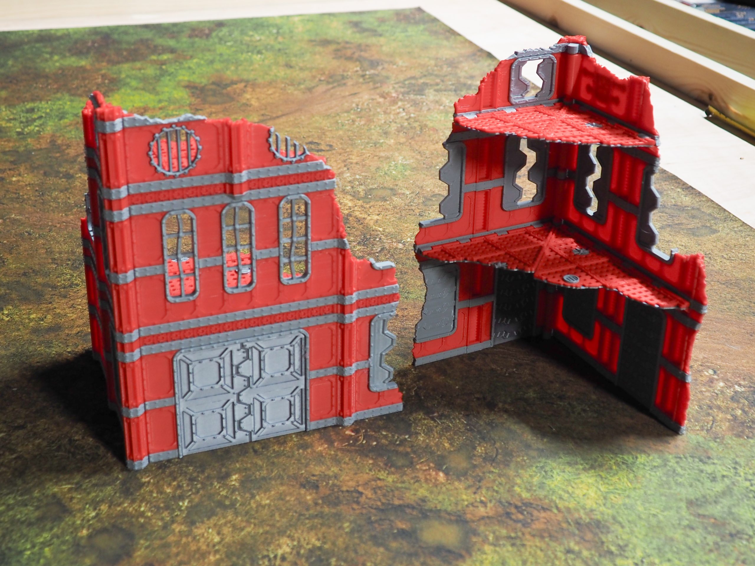 3D-printed ruined sci-fi building terrain for tabletop gaming, shown in red and grey with exterior and interior views
