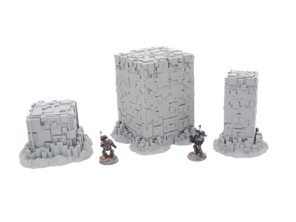 Three grey geometric sci-fi terrain pillars shown with painted miniature figures for scale