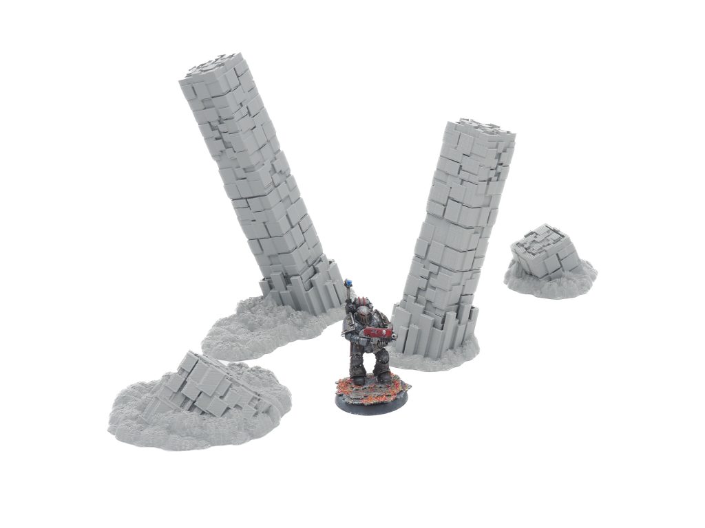 Grey 3D-printed basalt pillar terrain set for tabletop gaming, displayed with a painted miniature for scale